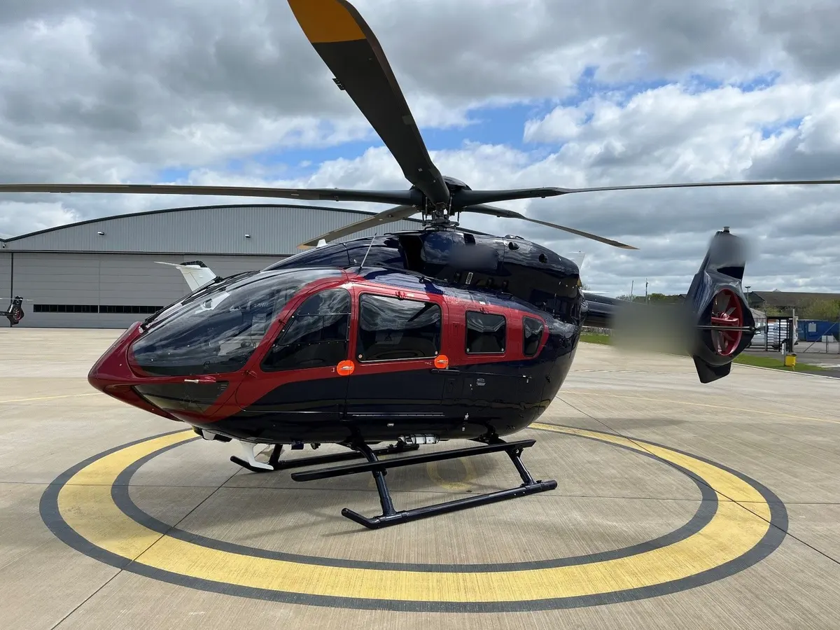 A dark helicopter with red trim on a yellow-ringed helipad