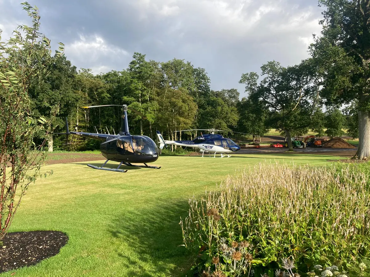 A helicopter parked on a lawn among trees